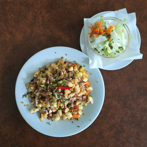 Bauernspätzle mit Speck, Zwiebeln, Pfefferoni und Beilagensalat.